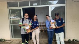 Um grupo de pessoas posando para foto com brindes natalinos em mãos